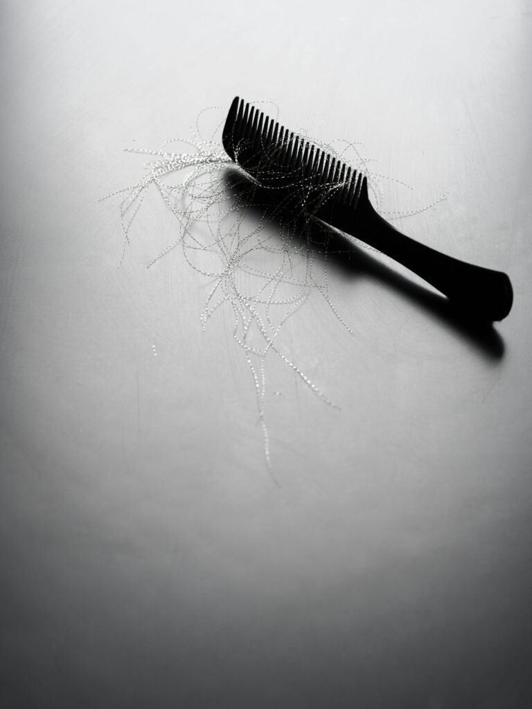 Pente preto com mechas de cabelo soltas, representando queda de cabelo