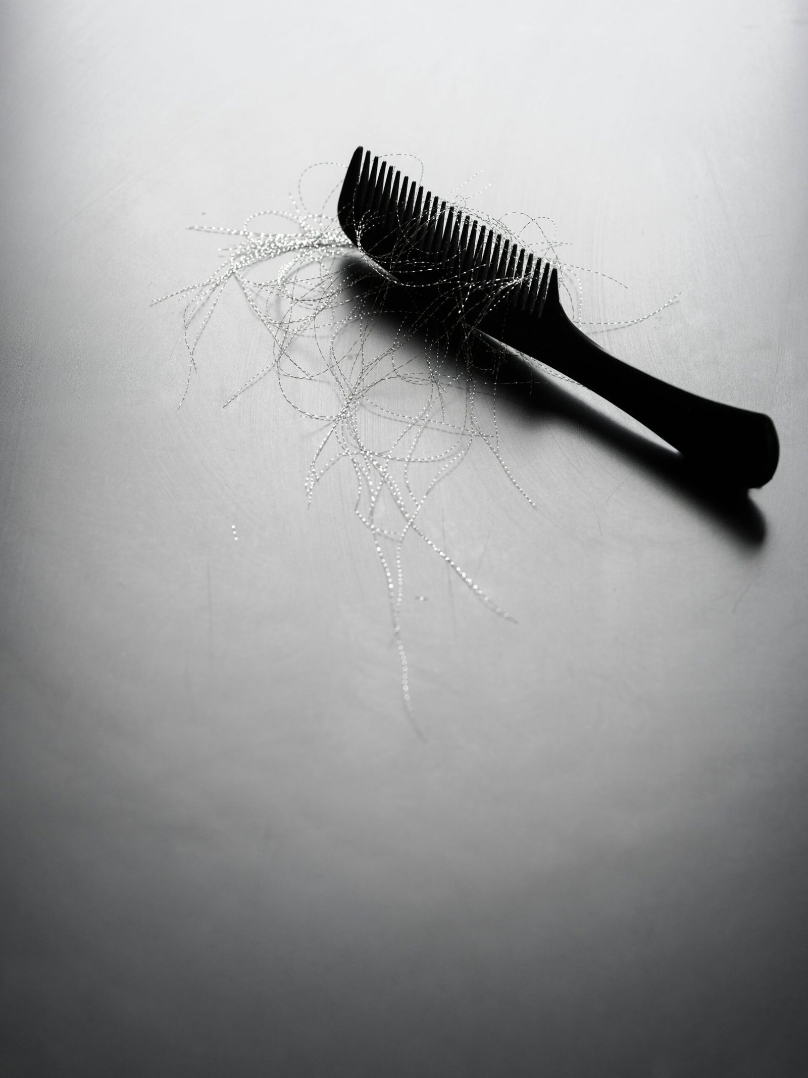Pente preto com mechas de cabelo soltas, representando queda de cabelo